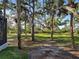 View of wooded yard with lush green grass and mature trees from the screened-in porch at 1769 Manasota Beach Rd, Englewood, FL 34223