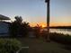 Backyard sunset view with mature trees, waterway, and lush landscape at 18382 Arapahoe Cir, Port Charlotte, FL 33948