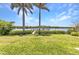 View of the backyard featuring a manicured lawn and a dock extending into the serene water at 18382 Arapahoe Cir, Port Charlotte, FL 33948
