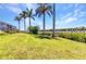 Expansive backyard with lush green lawn, mature palms, and waterfront views, offering a serene outdoor space at 18382 Arapahoe Cir, Port Charlotte, FL 33948