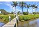 Private dock extending into the waterway, with lush landscaping and mature palms dotting the landscape at 18382 Arapahoe Cir, Port Charlotte, FL 33948