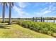 Waterfront view of a private dock extending into the canal, surrounded by verdant landscaping and swaying palm trees at 18382 Arapahoe Cir, Port Charlotte, FL 33948