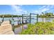 Waterfront property features a private wooden dock and boat lift on a tranquil canal with lush surroundings at 18382 Arapahoe Cir, Port Charlotte, FL 33948