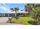 Charming home with a well-manicured lawn, palm trees, and a metal roof, showcasing curb appeal at 18382 Arapahoe Cir, Port Charlotte, FL 33948