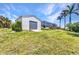 Property with a spacious detached garage and a screened-in lanai, set against a backdrop of palm trees and blue skies at 18382 Arapahoe Cir, Port Charlotte, FL 33948