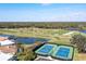 Aerial shot featuring tennis courts, a picturesque lake, and the surrounding golf course at 1903 San Silvestro Dr, Venice, FL 34285