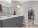 Bathroom featuring a double vanity with gray cabinets, marble countertop and an adjacent walk-in closet at 19800 Montenero Way, Venice, FL 34293