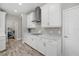 Modern kitchen features white cabinetry, herringbone backsplash, and stainless steel range hood at 19800 Montenero Way, Venice, FL 34293