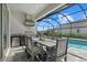 Covered outdoor dining area with stainless steel grill and mini fridge next to the screened-in pool at 19800 Montenero Way, Venice, FL 34293