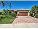 Inviting single-story home featuring a brick driveway, two car garage, and lush landscaping at 19911 Quisto St, Venice, FL 34293