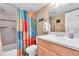 Bright bathroom features a white vanity, matching toilet, shower and colorful shower curtain at 200 The Esplanade N # B3, Venice, FL 34285
