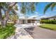 A spacious driveway leading to a single-story home with a screened lanai, lush landscaping, and mature trees at 2209 Woodmere Rd, Venice, FL 34293