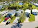 The aerial view features well-kept homes near a pond, and a red car and golf cart parked outside at 223 Lancer Dr, Nokomis, FL 34275