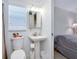 Clean bathroom with a pedestal sink, toilet, and view into adjacent bedroom at 223 Lancer Dr, Nokomis, FL 34275
