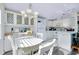 Bright dining area with white table set, chandelier, and white built in cabinets with glass doors at 223 Lancer Dr, Nokomis, FL 34275