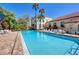 Community pool featuring lounge seating, mature landscaping, and building views at 238 Tampa W Ave # 217, Venice, FL 34285