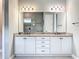 Bathroom featuring double sinks with granite counters and white cabinetry at 23823 Waverly Cir, Venice, FL 34293