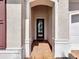 Covered entryway featuring an arched doorway, textured walls, and brick flooring leading to the front door at 23823 Waverly Cir, Venice, FL 34293
