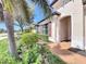 Inviting front entrance features an arched doorway and lush landscaping, including palm trees and flowering plants at 23823 Waverly Cir, Venice, FL 34293