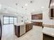 Well-lit kitchen features dark wood cabinets, stainless steel appliances, central island and seamless flow into living areas at 23823 Waverly Cir, Venice, FL 34293