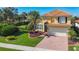 Well-maintained two-story home with lush landscaping, manicured lawn, and brick driveway at 23901 Waverly Cir, Venice, FL 34293