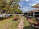 Landscaped backyard featuring a stone paver walkway, sunroom addition, and white privacy fence at 4070 Kincord Ln, North Port, FL 34287