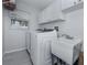 Well-lit laundry room with modern washer, dryer, utility sink, and ample white cabinet storage at 4070 Kincord Ln, North Port, FL 34287