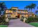 Elegant two-story home with lush landscaping, a brick driveway, and a grand entrance, creating a welcoming curb appeal at 416 Baycrest Dr, Venice, FL 34285