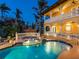 Exterior view showcasing the home's yellow stucco facade, balconies, swimming pool and lush tropical landscaping at 416 Baycrest Dr, Venice, FL 34285