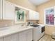 Bright laundry room featuring white cabinets, a utility sink, washer, dryer, and a window for natural light at 416 Baycrest Dr, Venice, FL 34285