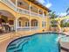 Beautiful pool and spa surrounded by a veranda, a built-in grill, lounge chairs and a lush tropical landscape at 416 Baycrest Dr, Venice, FL 34285