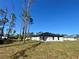 Home's backyard with large grass yard, a house and some trees at 4595 Horseshoe Ave, North Port, FL 34286
