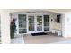 Condominium entrance with glass doors, a bench, and manicured landscaping, providing a welcoming first impression at 512 W Venice Ave # 102, Venice, FL 34285
