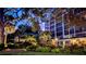 Condo building exterior at dusk, showcasing the well-lit landscaped grounds with palm trees and shrubbery at 512 W Venice Ave # 102, Venice, FL 34285