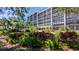 Condo building exterior featuring lush landscaping, water fountain and an American flag waving in the wind at 512 W Venice Ave # 102, Venice, FL 34285