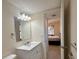 This bathroom includes a large mirror, updated vanity and lights, and tile flooring leading into bedroom at 519 Albee Farm Rd # 116, Venice, FL 34285