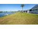 Home's waterfront backyard showcasing lush green lawn, lake view, and a dock at 6037 Shearwater Dr, Englewood, FL 34224