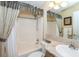 Well-lit bathroom with a shower-tub combo, patterned counter-top, and mirror for daily routines and relaxation at 6037 Shearwater Dr, Englewood, FL 34224