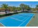Aerial view of a community tennis court featuring well-maintained blue and green surface, and palm tree surroundings at 6157 Midnight Pass Rd # D31, Sarasota, FL 34242