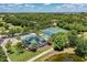 Aerial view of community pool, clubhouse, and tennis courts surrounded by lush landscaping at 6210 Cormorant Ct, Bradenton, FL 34203