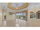 Expansive living room with a decorative ceiling, tiled floor, and views of the pool area at 6210 Cormorant Ct, Bradenton, FL 34203