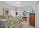 Bright bedroom with a floral quilt, ceiling fan, wood dresser and TV on the wall at 651 Back Nine Dr, Venice, FL 34285