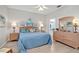 Bright bedroom with a blue quilt, ceiling fan, wood dresser and ensuite bathroom at 651 Back Nine Dr, Venice, FL 34285