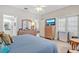 Bright bedroom with a blue quilt, ceiling fan, wood dresser and TV on the wall at 651 Back Nine Dr, Venice, FL 34285