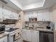 Well-lit kitchen showcasing white cabinetry, mosaic backsplash, and stainless steel appliances at 66 Boundary Blvd # 275, Rotonda West, FL 33947