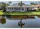 Home featuring a screened-in lanai with a view of a serene pond and well-maintained landscaping at 692 Egret Walk Ln, Venice, FL 34292