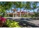 Exterior view of the clubhouse features a red tile roof, stately columns, and lush tropical landscaping at 692 Egret Walk Ln, Venice, FL 34292