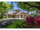 Exterior view of the clubhouse features a red tile roof, stately columns, and lush tropical landscaping at 692 Egret Walk Ln, Venice, FL 34292