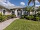 Stately front entrance with manicured lawn and lush tropical landscaping at 692 Egret Walk Ln, Venice, FL 34292