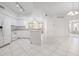 Open kitchen with white cabinetry, appliances, an island with seating, and tile flooring connecting to other rooms at 7104 L Pavia Blvd # 7104, Venice, FL 34292
